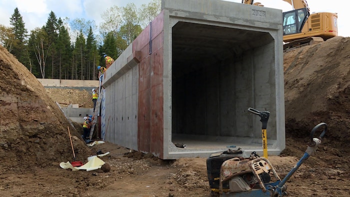 Des ouvriers installent la structure de béton à un endroit où la route est coupée.