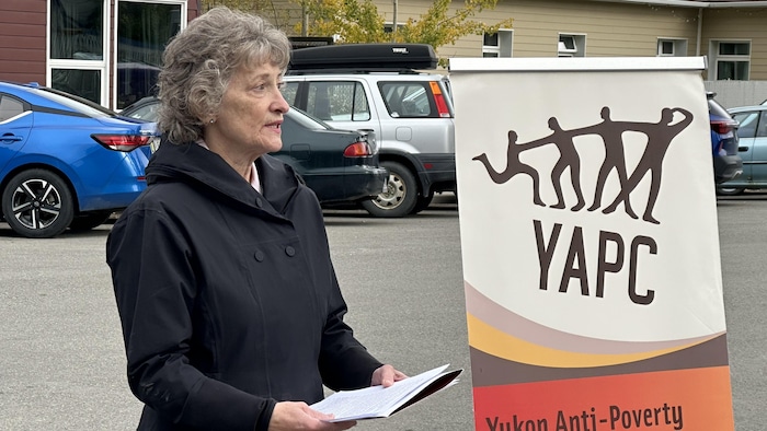 Pat Duncan est dans la rue, des papiers dans les mains.