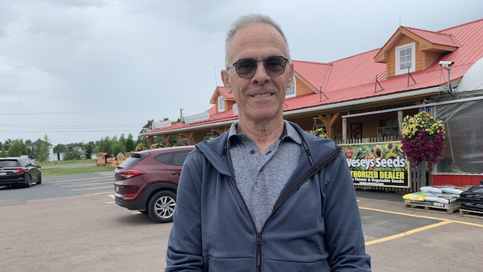 Un homme debout dehors dans le stationnement d'un magasin vendeur de graines.