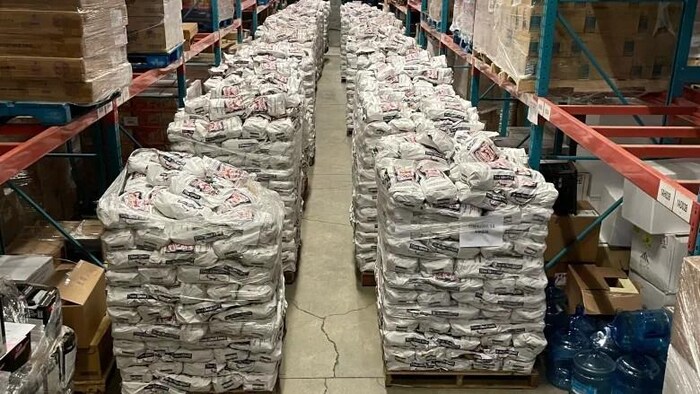 Une cargaison de centaines de sacs de pommes de terre dans un entrepôt.