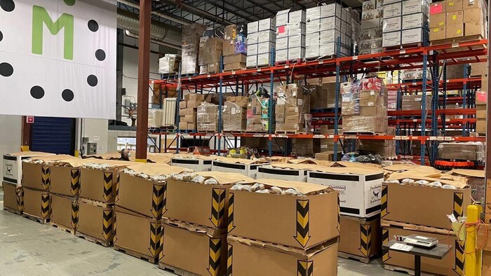 Des sacs de patates dans des dizaines de boîtes de carton alignées dans un entrepôt.
