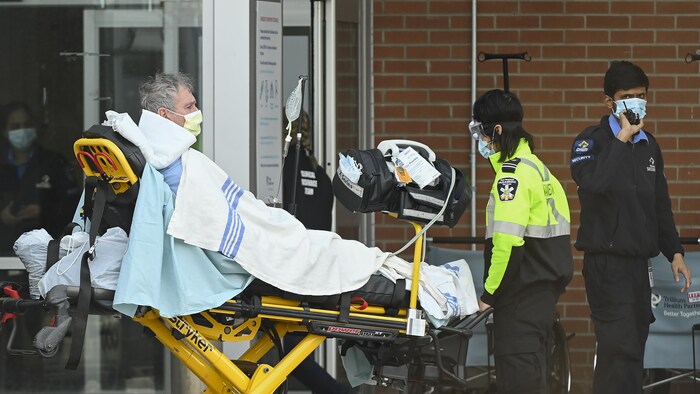 Des ambulanciers amènent un patient à l'hôpital sur une civière, à Mississauga.