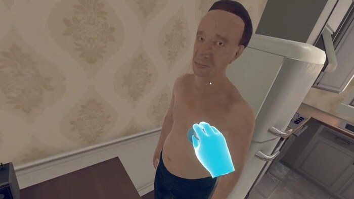 On voit une image de réalité virtuelle représentant un patient qui se tient debout dans sa cuisine. Un curseur en forme de main est visible au centre de l'image.