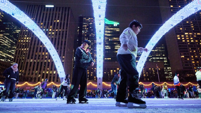 Des visiteurs patinent lors de la soirée d’ouverture de la Cavalcade des lumières annuelle au Nathan Phillips Square, à Toronto, le samedi 29 novembre 2025.