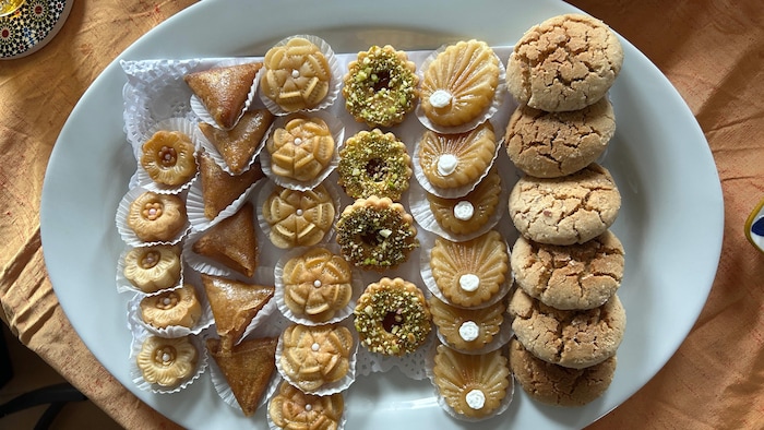 Une assiette ovale photographiée de haut. Elle contient plusieurs différents desserts et biscuits marocains.