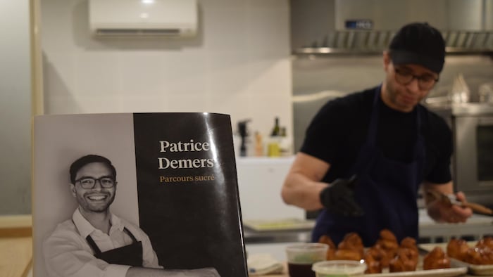 Patrice Demers cuisine derrière un livre.