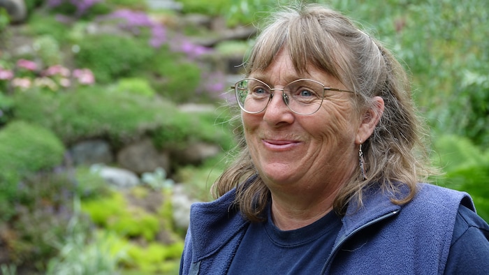 Photo portrait du visage de Patricia Gallant, devant une plate-bande fleurie.