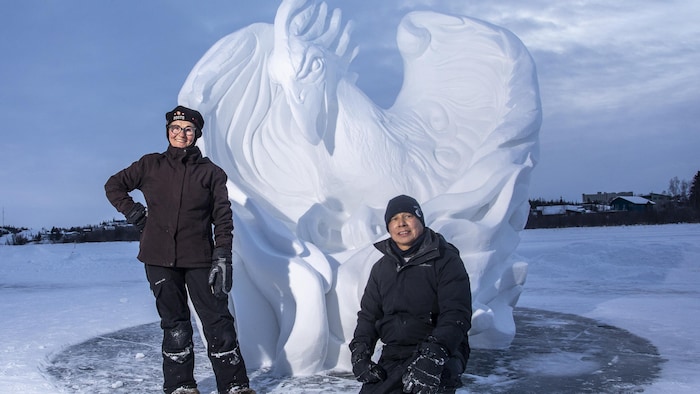 John Sabourin et Patricia Leguen devant une sculpture en neige en forme d'aigle. 