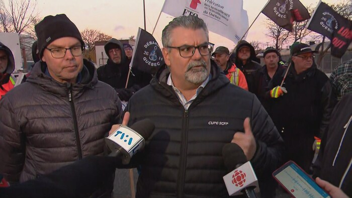 A man is pressing the press surrounded by employees. 
