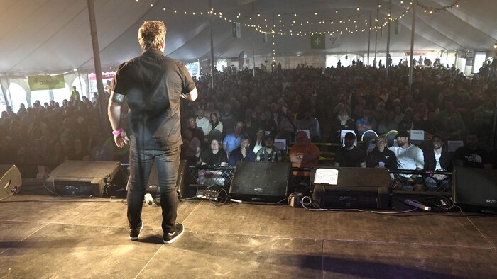 Patrick Groulx parle à un public devant une salle pleine.
