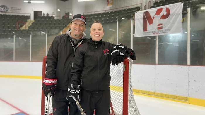 Patrick Laferrière et Melissa Samson posent à la caméra devant un filet de hockey sur une patinoire.