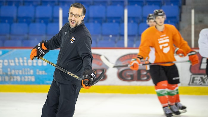 L'entraîneur des Patriotes de l'UQTR, Marc-Étienne Hubert, sur la glace, bouche ouverte en train de parler à ses joueurs, avec deux joueurs en arrière-plan