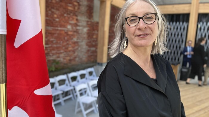 La ministre Patty Hajdu pose à côté du drapeau canadien. 
