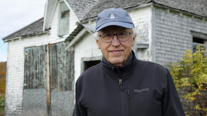 Paul Lemieux photographié devant l'école du 2e Rang de Carleton-sur-Mer.