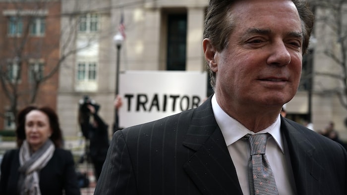 Paul Manafort quitte le tribunal, en compagnie de sa femme, Kathleen. En arrière-plan, un protestataire tient une pancarte sur laquelle on peut lire : « Traître ».