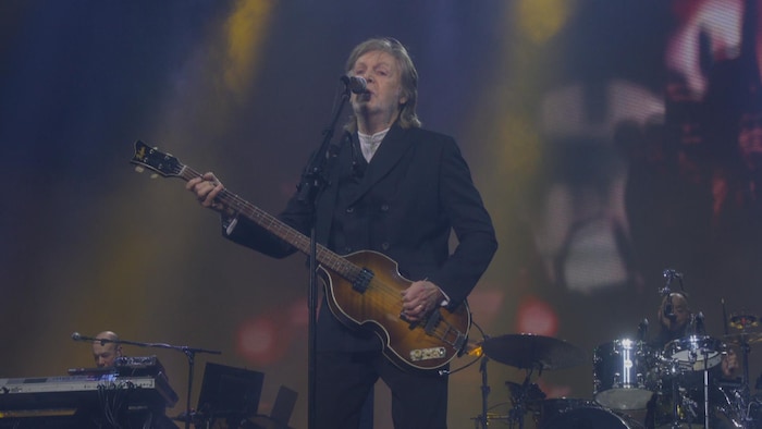 Un homme joue de la guitare sur scène.
