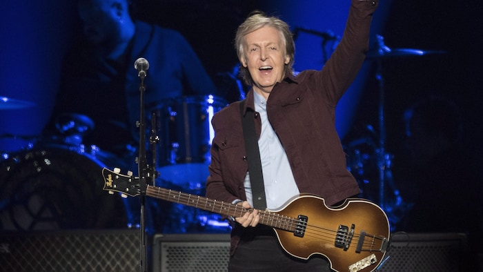 Sa guitare sur lui, Paul McCartney salue le public de la main.