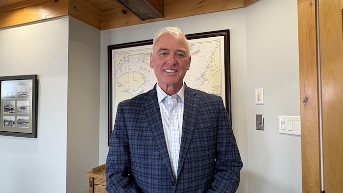 Paul Robichaud pose pour la photo devant une carte du Golfe du Saint-Laurent.