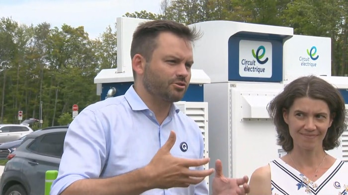 Paul St-Pierre Plamondon parle et gesticule près d'une borne de recharge électrique.