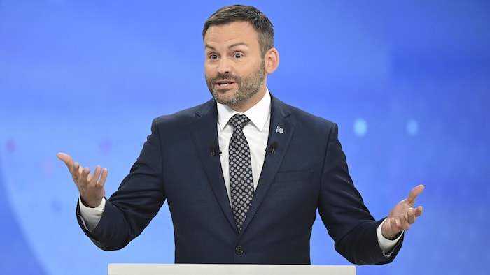 Paul St-Pierre Plamondon s'exprime derrière son pupitre en ouvrant les bras.