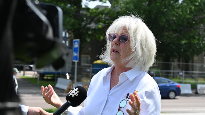 Une personne aux cheveux blancs en entrevue. 