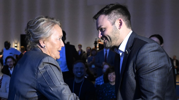 Pauline Marois and Paul St-Pierre shake hands in front of Plamonton supporters.