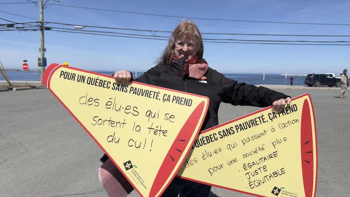 Portrait de Dominique Bouchard portant des pancartes.