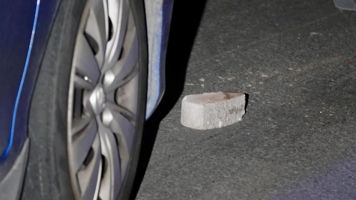 Un pavé sur le sol, à côté d'une roue de voiture.