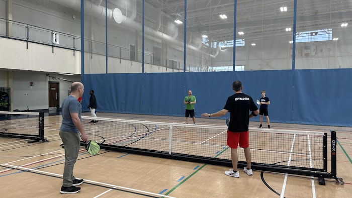 Des joueurs de pickleball écoutent les instructions d'un entraîneur.