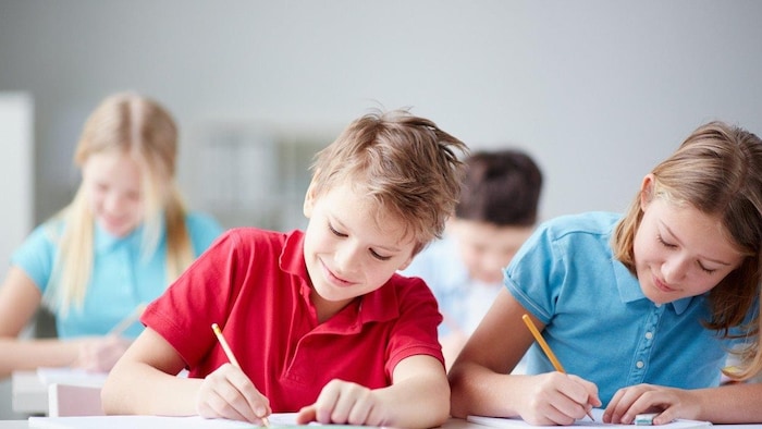 Un garçon et une fille souriants écrivent à l'école