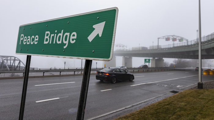 Un panneau routier avec le nom du pont, avec le pont à l'arrière.