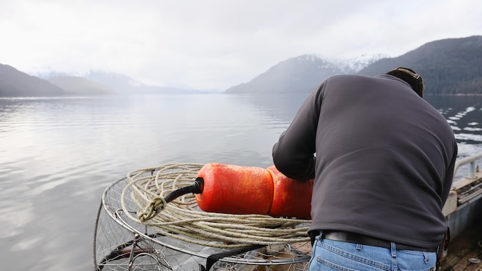 Un pêcheur prépare un piège à crabe.