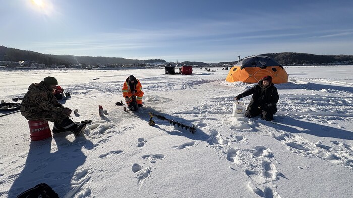 trois pêcheurs en hiver avec leur équipement sur une baie glacée