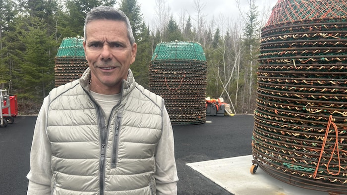Un homme souriant devant des casiers de pêche au crabe.