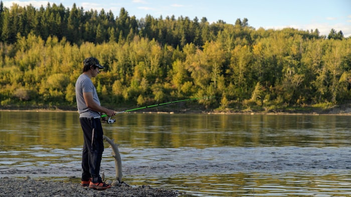 Un homme avec une canne à pêche près d'une rivière.