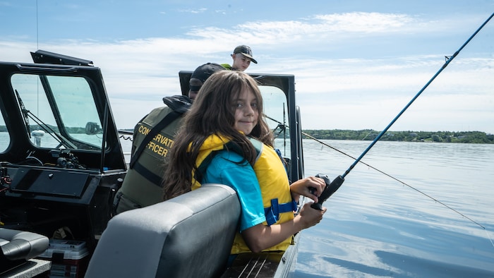 Une enfant tient une canne à pêche dans un bateau sur le lac Whitewater, à Azilda.