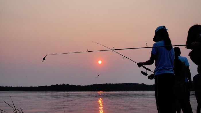 Des pêcheurs pêchent au coucher du soleil.