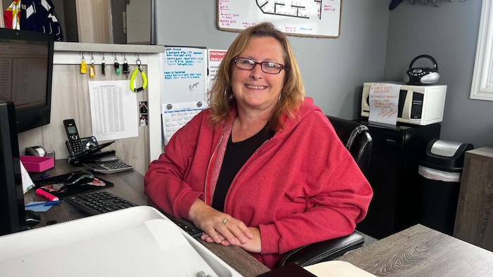 Une femme souriante assise à son bureau.