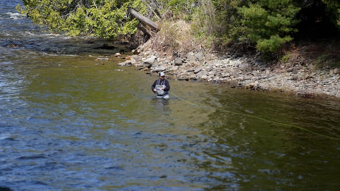 Un homme dans la rivière qui pêche.