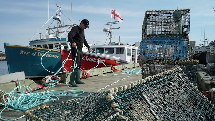 Pêcheur sur le quai avec des cordages et des casiers à homard.