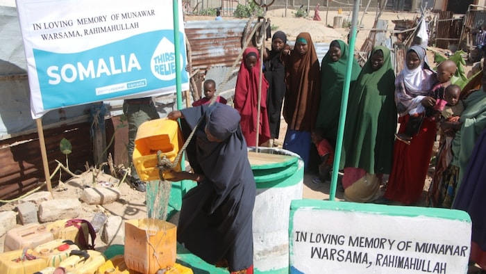 Une femme se ravitaille en eau à un puits en Somalie.