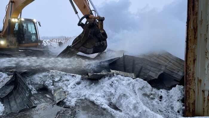 Une pelle excavatrice sur des débris brûlés.