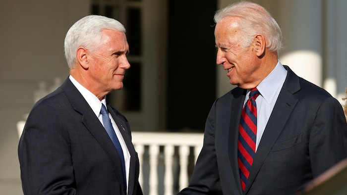 Joe Biden et Mike Pence, sourient, l'un face à l'autre. 