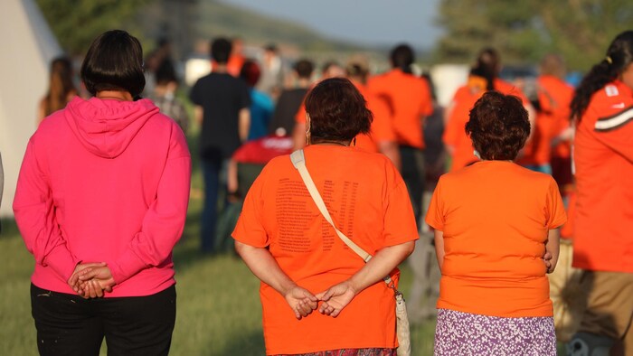 وقفة تأملية نرى المشاركين فيها من الخلف وكثيرون منهم يرتدون قمصاناً برتقالية اللون.