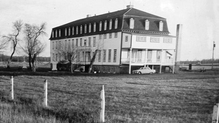 Une vieille photo en noir et blanc montre le bâtiment de trois étages. 