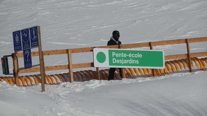 Un planchiste se laisse monter sur un tapis roulant neuf de la station de ski Pin Rouge.