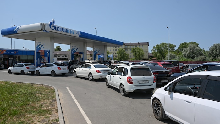 Une file de voitures devant une station de service.