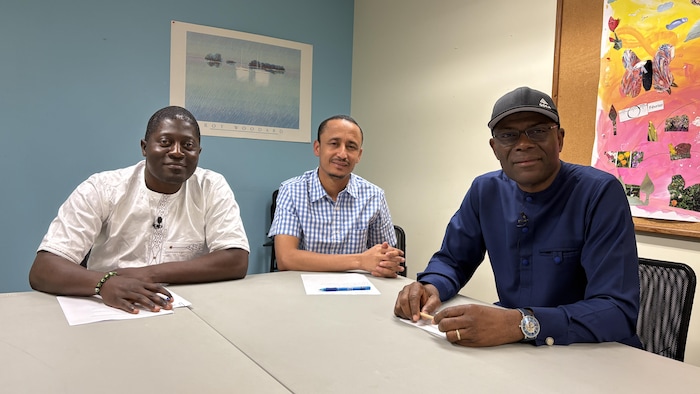 Trois hommes dans une salle de conférence.