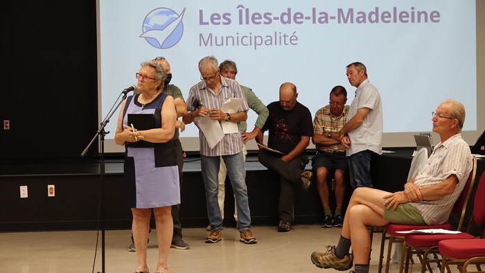 Des citoyens alignés derrière un micro durant une période de questions.