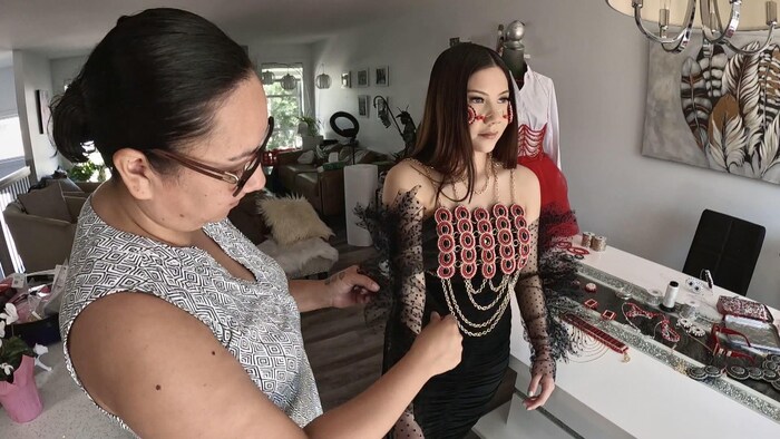La perleuse autochtone Helen Oro installe l'une de ses œuvres sur une mannequin en mai 2023.